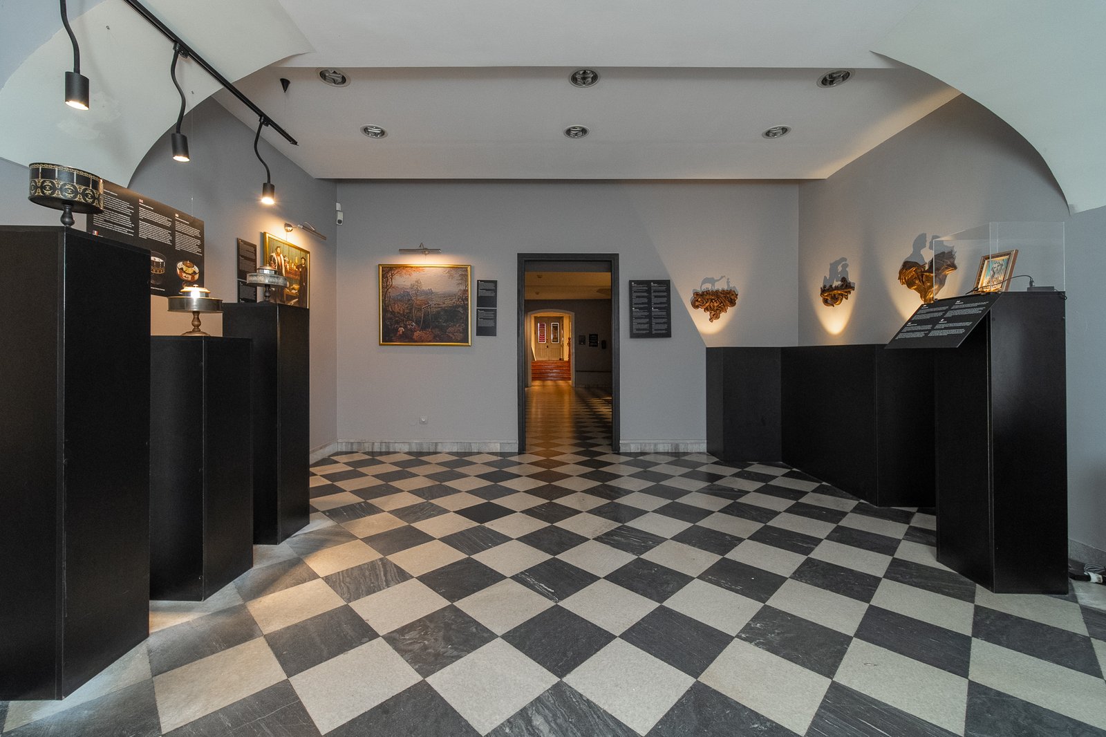 Sala z historycznymi przyrządami optycznymi na czarnych postumentach i szachownicową posadzką w Muzeum Iluzji Krakil w Krakowie